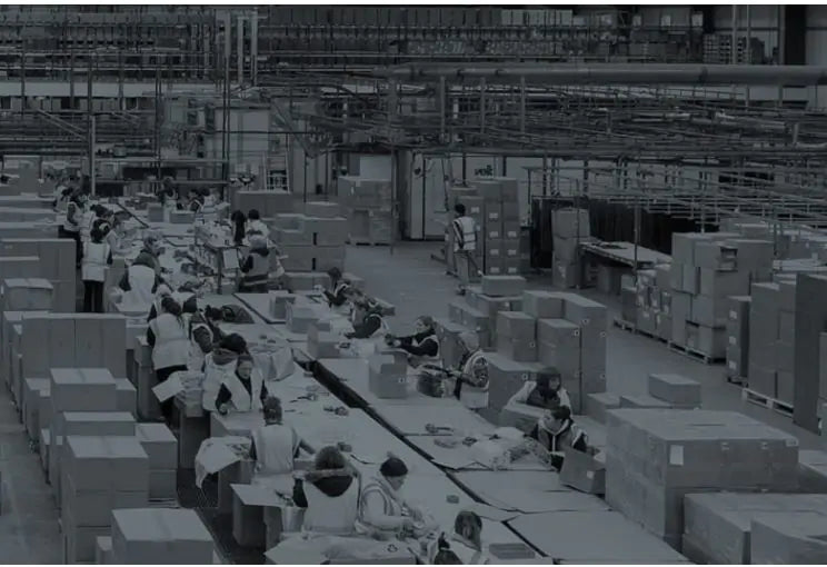 Warehouse interior with workers and boxes, likely a distribution center.