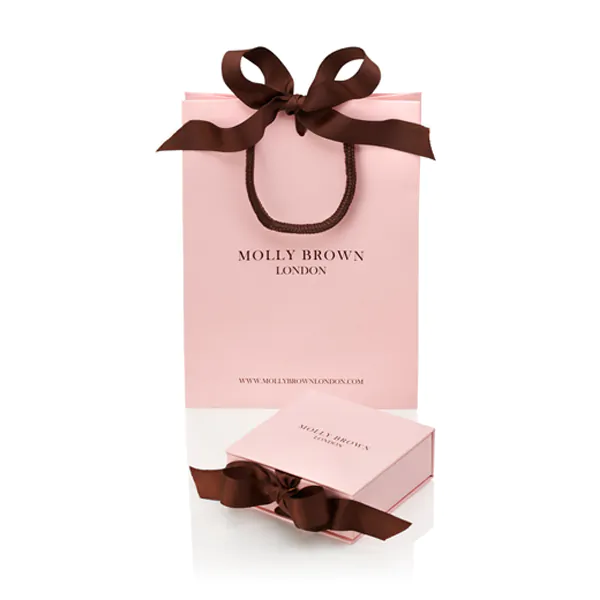 Pink gift bag with brown ribbon and 'Molly Brown London' branding on a white background